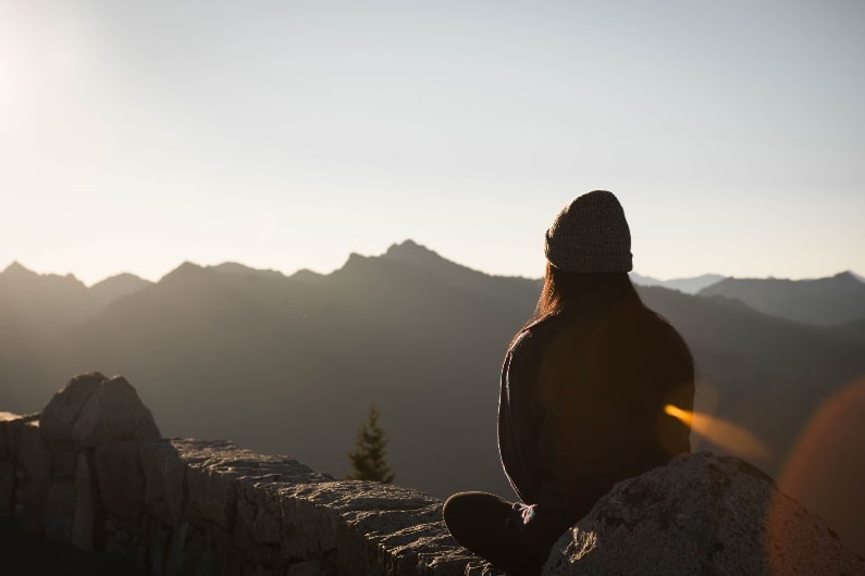girl meditating in the mountains - benefits of meditation